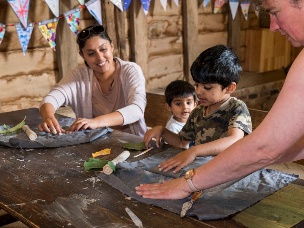 two children and a mother working led by the artist during the pottery workshop